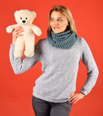 Kadın kırmızı arka planda oyuncak ayıyı tutuyor..