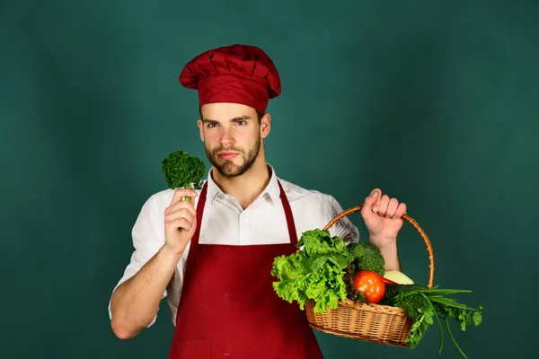 Koch in Küche hält Brokkoli und Korb mit frischem Gemüse. — Stockfoto