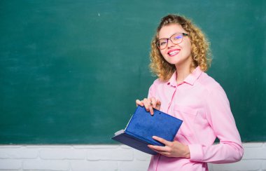 Öğretmen zor konuyu açıkla. Pedagog kitabı tutuyor ve bilgiyi açıklıyor. Eğitim konsepti. Karatahtanın önündeki kadın öğretmen. Öğrencilerin en iyi öğretmeni. Bilgiye karşı tutkulu