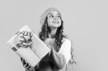 Çocuk hediye kutusunu tut. Alışveriş merkezi konsepti. Doğum günü kutlaması fikri. Keyfin yerinde. Doğum günü geleneği. İyi tatiller. Neşeli küçük kız örgü şapka ve kazak örüyor. Doğum günü sürprizi