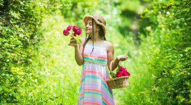 Harika bitkiler. Anneler Günü. Mutlu kadınlar günü. Çiçekli küçük bir çocuğun portresi. Aşk ve güzellik. Bir buket gül çiçeğiyle göz kamaştırıcı bir kız. Hasır şapkalı mutlu çocuk. Doğanın saç stili