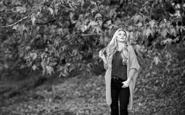 Hafta sonu için samimi kıyafet fikirleri. Kadın gün batımında yürüyor. Sonbaharda giymek için rahat kıyafetler. Rahat bir kıyafet. Sevimli sarışın kız, sıcacık ve rahat pozlar veriyor. Sonbahar doğasının arka planı çözüldü.