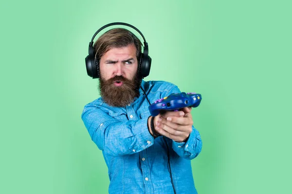 Adding Fun to your Life. male in headphones with game console. computer gaming concept. playing online. relax with favorite hobby. bearded man gamer. cheerful man wear modern earphones