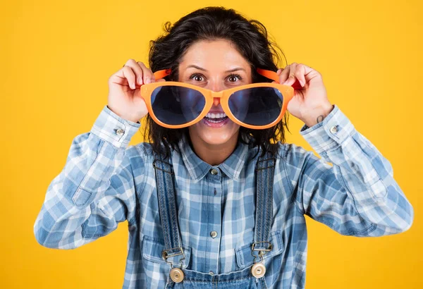 Déjame ver la fiesta. chica sobre fondo amarillo. sonrisa alegre y encantadora. estudiante divirtiéndose. Retrato de moda mujer bastante joven. mujer hipster en gafas de fiesta divertidas. tendencias casuales y denim —  Fotos de Stock