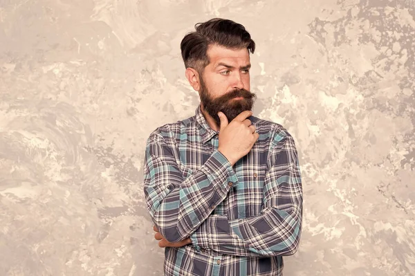 Homem raspado se importa com seu olhar. cabeleireiro profissional em camisa quadriculada. homem barbudo brutal grunge fundo. homem sério com barba exuberante e bigode. confiante masculino hipster após barbearia — Fotografia de Stock