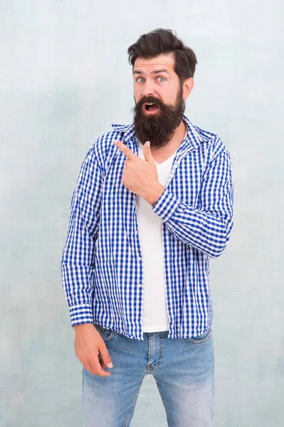 Έκπληκτος hipster με τρίχες γενειάδας σε casual στυλ ένδειξη χειρονομία δάχτυλο σε μπλε φόντο, δείχνοντας — Φωτογραφία Αρχείου