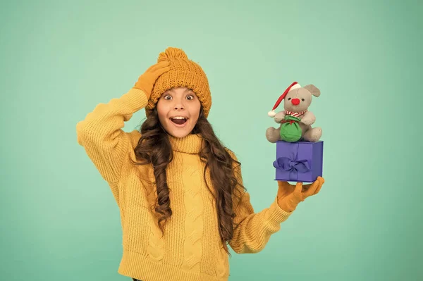 Dárek pro štěstí. Úspěšný krysí rok. Usmířit se dárkem. Nákupní tipy. Happy girl hold mouse toy and wrapped gift box. Kid pletený svetr a klobouk hrát plyšovou hračku. Nakupujte pro děti. Šťastný rok 2020 — Stock fotografie