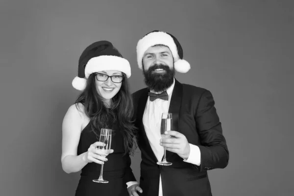 Őszinte üdvözletem. Boldog karácsonyt! Irodai buli. Egy pár a céges bulin. Boldog új évet! Szakállas üzletember szmokingban és lány elegáns ruha iszik pezsgő vörös háttér. Téli parti — Stock Fotó