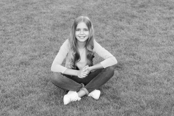 Menina adolescente após cabeleireiro. relaxar na grama verde. tempo de lazer primavera. infância feliz. criança com cabelo elegante. Sorriso alegre. menina feliz tem cabelo encaracolado longo. criança beleza e moda — Fotografia de Stock