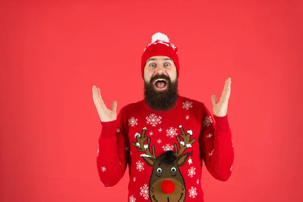 Boldog új évet! Csatlakozz a téli ünnephez. Karácsonyi pulcsi parti. Téli ruha. Szórakoztató tevékenységek és elfoglaltságok. Hipster érzelmi szakállas férfi visel téli pulóver és kalap piros háttér — Stock Fotó