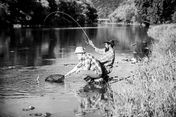 Σπινθηροβόλα. μύγα ψάρια χόμπι των ανδρών σε καρό πουκάμισο. αλιεία απόσυρσης. Χαρούμενη φιλία ψαράδων. Δύο αρσενικοί φίλοι ψαρεύουν μαζί. Πιάσιμο και ψάρεμα. συνταξιούχος μπαμπάς και ώριμος γενειοφόρος γιος — Φωτογραφία Αρχείου
