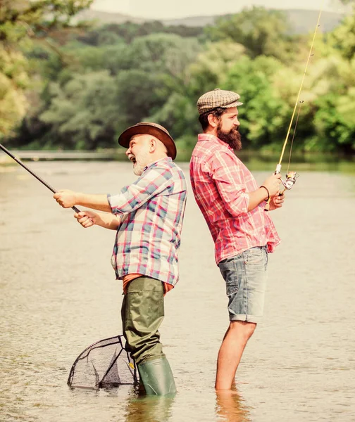 Generazioni. weekend estivo. uomini maturi pescatore. amicizia maschile. legame di famiglia. hobby e attività sportive. Esche di trota. padre e figlio pesca. due pescatori felici con canna da pesca e rete — Foto Stock