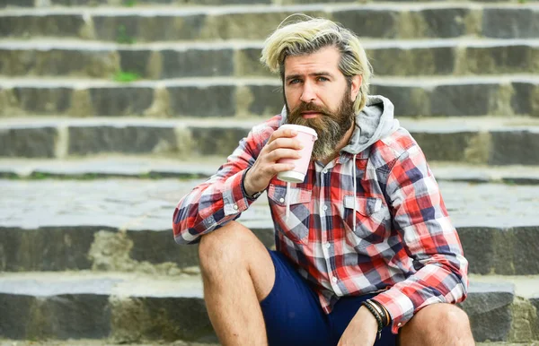 Cultura do café da terceira onda. Um homem com barba a beber café. Homem barbudo beber café fundo urbano. Hipster relaxe nas escadas. Descansar. Tira o café. Puro prazer. Dose de cafeína. Bom humor. — Fotografia de Stock
