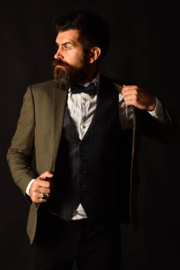 Eskimiş şık takım elbiseli ve kahverengi arka planda yelek giyen adam..