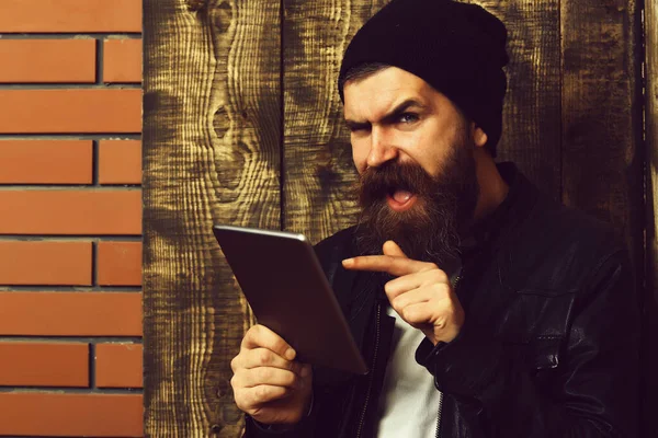 Kahverengi, eski, ahşap stüdyo arka planında tablet tutan Kafkasyalı vahşi hippi.