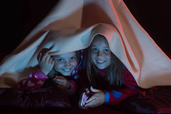 Concepto de infancia y felicidad. Niños en pijama cubiertos con manta — Foto de Stock