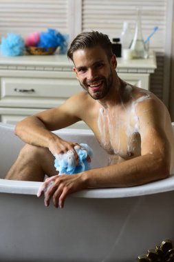 Çekici gülüşü olan, küvette çıplak oturan, seçici odaklı maço.