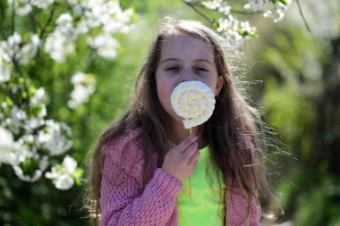 Pembe kazaklı çocuk beyaz lolipop yiyor. Öğrenci kız dışarı çıkıyor.