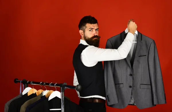 Tailor με σοβαρό πρόσωπο κρατά γκρι κοστούμι κοντά custom σακάκια — Φωτογραφία Αρχείου