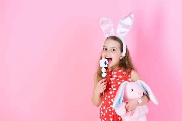 Flicka slickar klubba godis med kanin på rosa bakgrund — Stockfoto