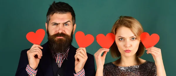 Atraente jovem casal segurando corações vermelhos perto dos olhos — Fotografia de Stock