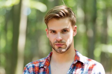Sakallı, genç yüzlü, çekici bir adam. Teni ve şık saçları var. Yaz manzarasında sıradan bir tarzı var.