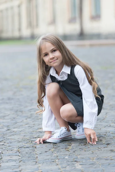 Malé dítě s dlouhými vlasy ve školní uniformě hrát ve školním dvoře venku, dětství — Stock fotografie