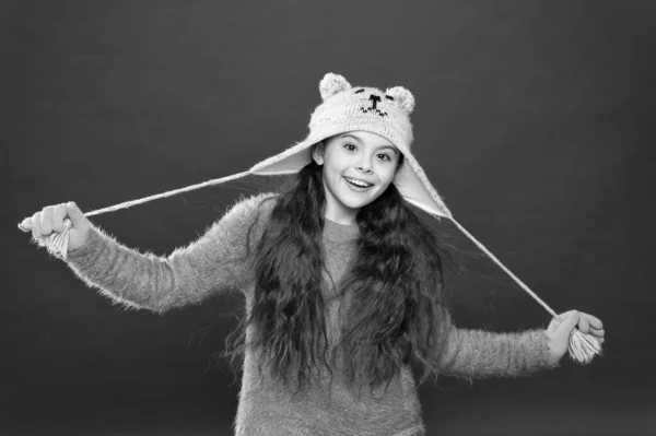 Schattig model genieten van de winter stijl. Teddy beer. Schattige beer zijn. Winterkleding. Kleine jongen draagt gebreide hoed. Blijf warm. Meisje winter mode accessoire. Klein kind lang haar dragen hoed rode achtergrond — Stockfoto