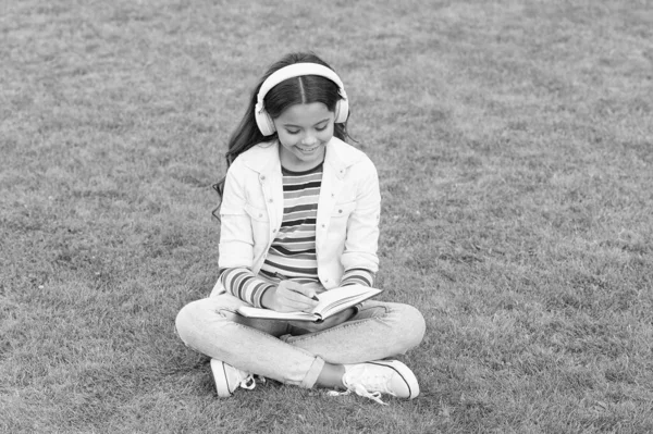 Çevrimiçi öğrenme. Eğitici podcast. Hallet şu işi. Açık havada müzik dinlemek. Çocuk müzikten hoşlanıyor. Çayır gibi otur. Keyifli zaman. Çocuk kulaklıkları müzik dinler. Havalı kız kulaklıkları müzik dinliyor.