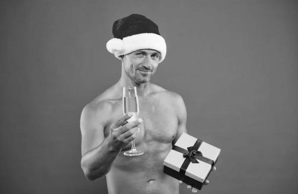 Na zdraví šampaňského. Pohledný muž drží vánoční dárek. Atletický Santa s vhodným trupem a dárkovou krabicí. Perfektní romantický dárek na Nový rok. Boxerský den. Dovolená — Stock fotografie