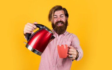 Bu senin için. Sakallı adam kırmızı elektrikli su ısıtıcısı kullanıyor. Erkek ev idaresi konsepti. Sıcak suya ihtiyacım var. Adam çay ya da kahve içecek. Bıyıklı ve sakallı vahşi bir adam. elektrikli ev aygıtı