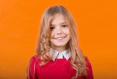 Turuncu arka planda kıvırcık sarı saçlı çocuk.