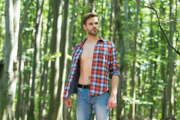 Samotny przystojny facet z seksownym gołym tułowiem w otwartej koszuli casual stylu stoją w lesie w słoneczny letni dzień naturalny krajobraz, człowiek — Zdjęcie stockowe
