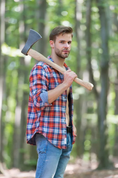 Pria berjenggot dengan kemeja kotak-kotak dengan celana jeans membawa kapak pemisah besar di lingkungan alam kayu musim panas, penebang — Stok Foto