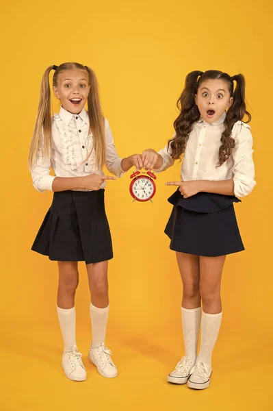 Het is tijd. Schoolrooster. Schoolmeisjes en wekker. Kinderen scholieren. Kennisdag. School tijd. Verrassend dat schokkende kinderen de wekker tellen. De laatkomer wordt gestraft. — Stockfoto