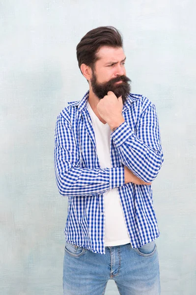 Lost in thoughts. Serious look of bearded man. Serious hipster with beard blue background. Solving problem. Dilemma. Thinking process. Barbershop. Hair salon. Casual style. Fashion wear