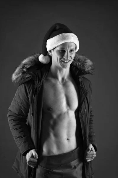 Take off winter jacket. Healthy body. Santa claus diet. Athlete man wear santa hat. Sexy athletic macho in santa claus hat. New year party erotic show. Bodybuilder santa claus. Macho sexy torso — Stock Photo, Image