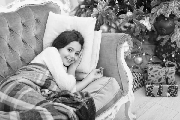 Мечтал о подарках. Маленькая девочка лежала на диване возле елки красивый интерьер. Волшебный момент. Волнуюсь перед Рождеством. С Новым годом. Семейный праздник. Рождественская елка и подарки — стоковое фото