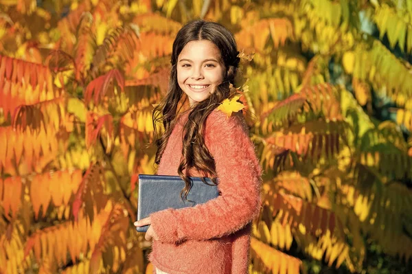 Keep studying. Small girl read book on autumn day. Autumn literature concept. Small child enjoy reading autumn foliage background. Little child enjoy learning in autumn park. Kid study with book