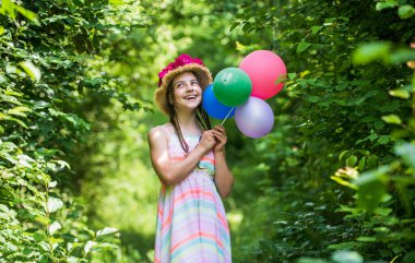 Bahar parkında ya da bahçede çocuk yürüyüşü. Şapkalı küçük bir kız. Yaz tatili ve tatil. Kadın güzelliği ve moda. çocukluk mutluluğu. Parti balonlu mutlu çocuk. Güzellik bahçesi.