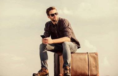 Hazır olduğunuzda. Gözlüklü iş adamı. İş gezisi. Maço turist rahat tur çantası. Seksi adam gökyüzü arka planı telefonda konuşuyor. Gezgin, taksi bekle. Çekil şuradan. Erkek modası. Çok moda görünüyor.