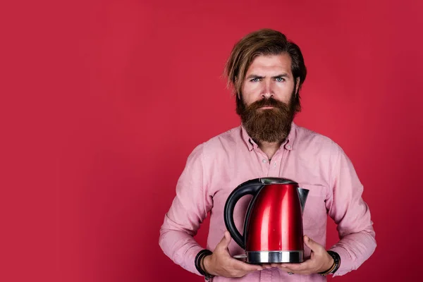 bearded man shop assistant presenting kitchen utensil. useful in housekeeping. mature charismatic male use electric kettle. guy with beard and moustache make tea. drink hot tea. copy space