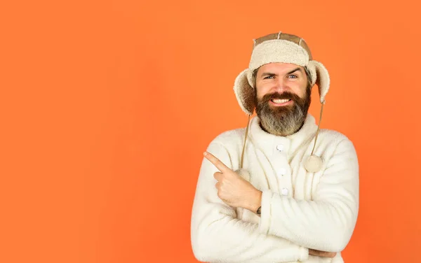 fashion clothes for cold weather. mature hipster orange background. male fashion style. autumn weather forecast. earflap hat protect from cold. bearded man wear winter hat. copy space. Feeling rested