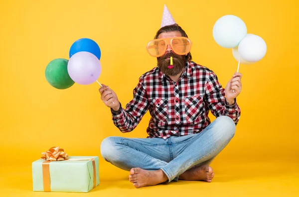 Concepto de diversión y felicidad. hombre feliz sosteniendo globos de helio de colores. hipster sonriendo felizmente. divirtiéndose en la fiesta. prepararse para las vacaciones. Gerente de eventos posa con accesorio festivo —  Fotos de Stock
