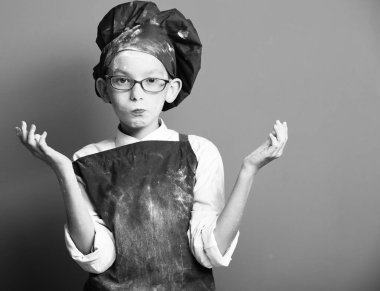 Kırmızı stüdyo arka planında lekeli aşçı çocuk.