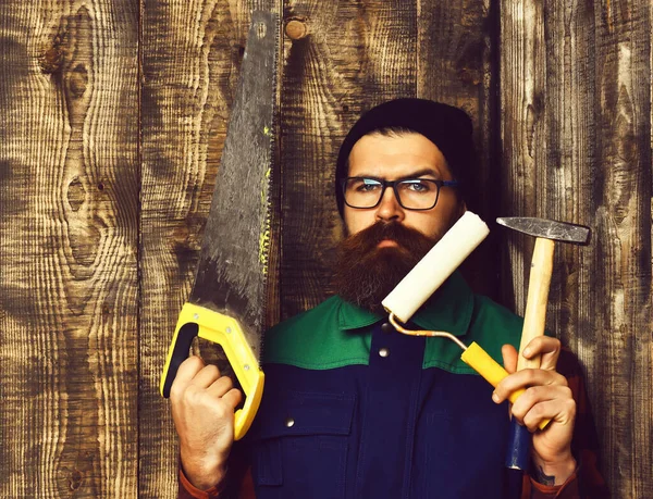 Бородатый художник держит различные строительные инструменты с серьезным лицом — стоковое фото