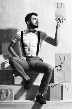 Sakallı adam merdivenlerde oturuyor, ciddi bir yüzü var.