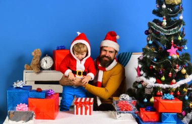 Noel Baba ve küçük yardımcısı Noel ağacının yanındaki hediye kutularının arasında.