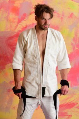 Adam siyah kuşak taşıyan beyaz kimono giymiş.