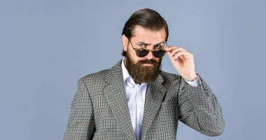 Yakışıklı adam ofis kıyafeti giyer. Erkek güzellik ve moda. Mükemmel sakallı ve bıyıklı acımasız bir iş adamı. Ceketli gerçek patron. Olgun adam gözlük takıyor. Güven ve karizma. Genç uzmanlık